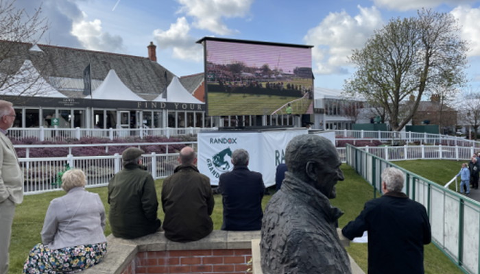 people watching grand national on screen 2022 at the racecourse