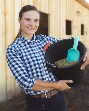 horse feed in a bucket being held by a woman